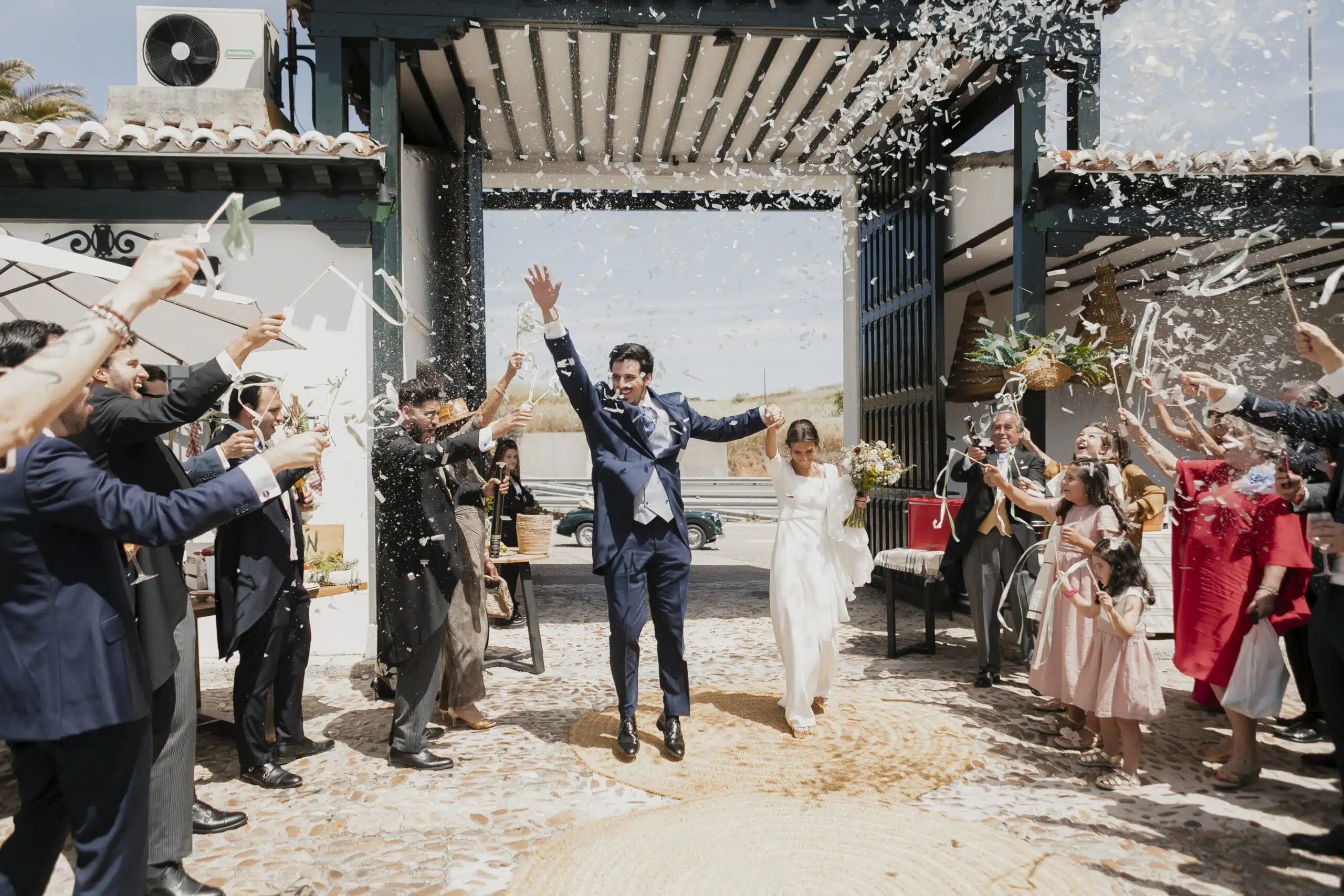 Pareja de novios saliendo entre invitados y lluvia de confeti