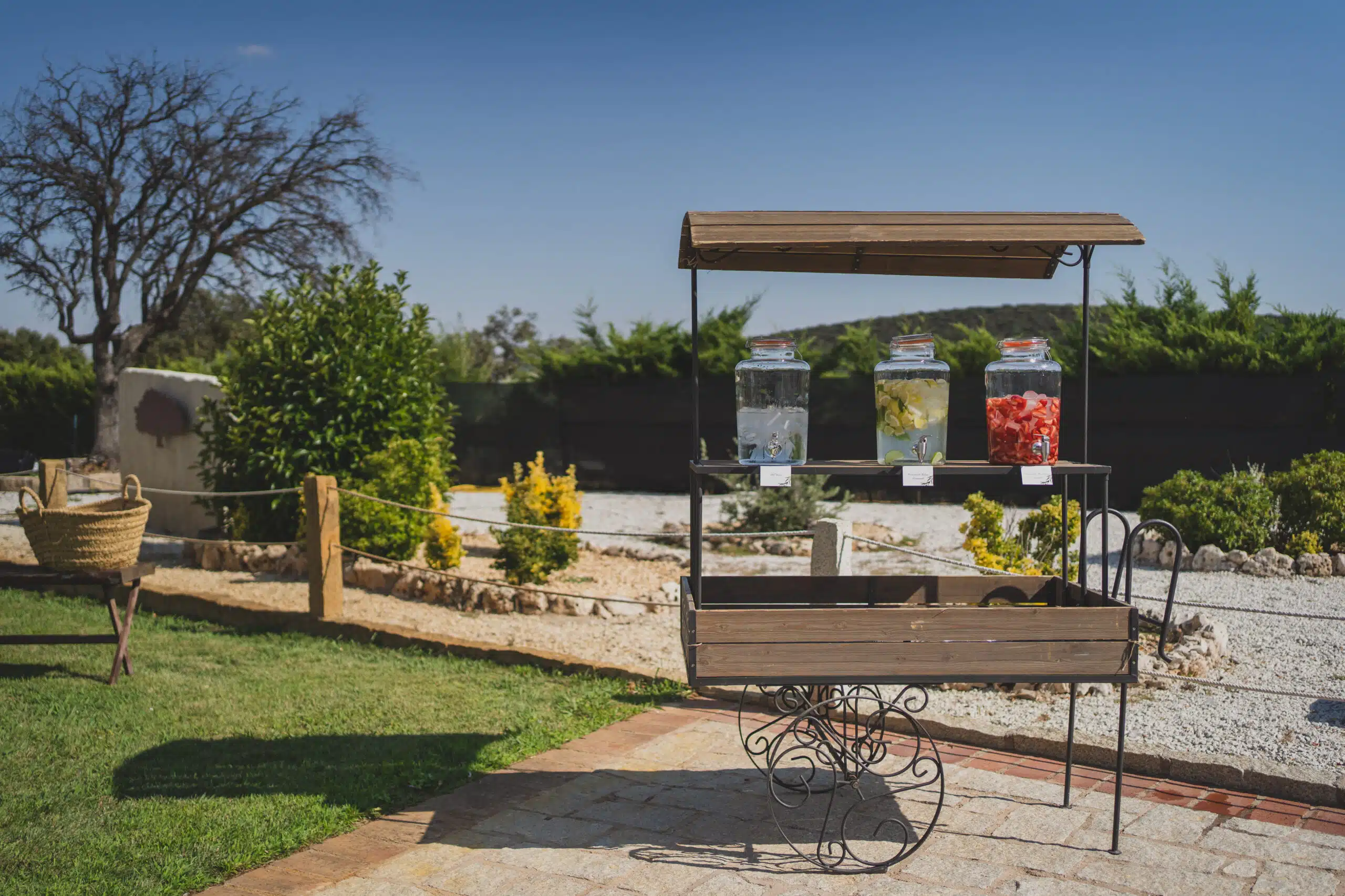Carrito rústico de madera con dispensadores de bebidas en jardín exterior